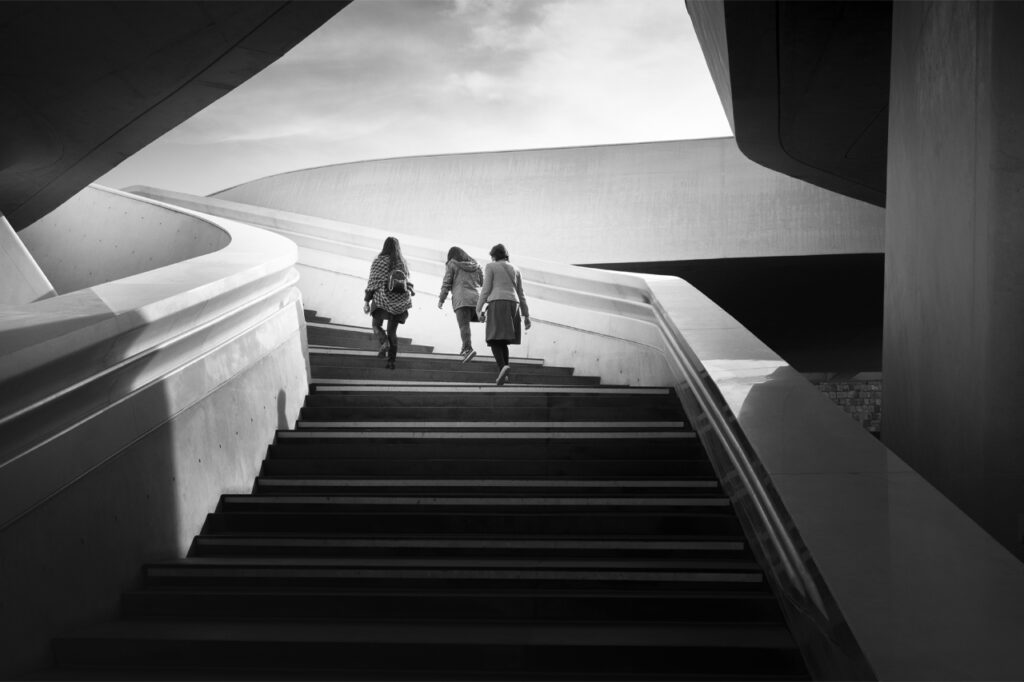A black and white photograph showing three girls walking up an external staircase